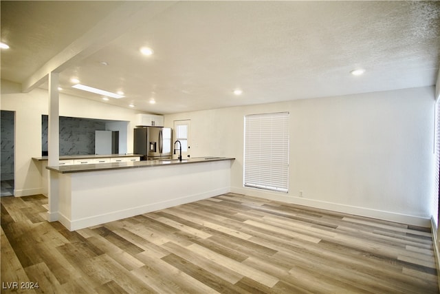 kitchen featuring kitchen peninsula, stainless steel refrigerator with ice dispenser, light wood-type flooring, and white cabinets