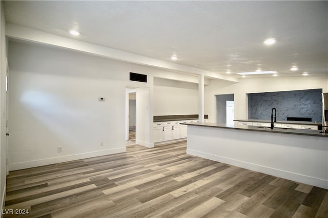 unfurnished living room featuring sink, vaulted ceiling, and light wood-type flooring