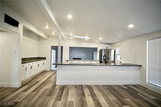 kitchen featuring kitchen peninsula, stainless steel refrigerator with ice dispenser, lofted ceiling with beams, and white cabinetry