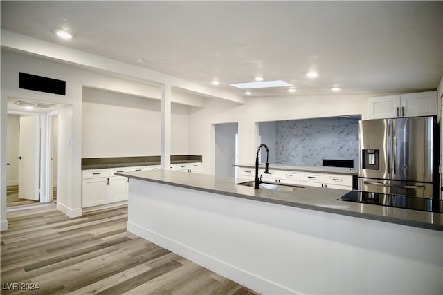 kitchen featuring white cabinets, sink, stainless steel refrigerator with ice dispenser, and light hardwood / wood-style flooring