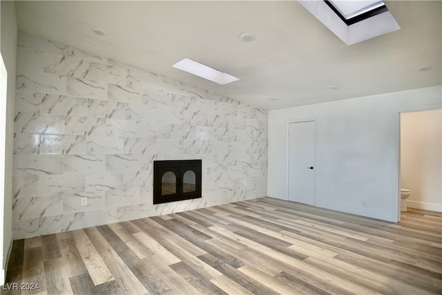 unfurnished living room featuring hardwood / wood-style floors and a skylight