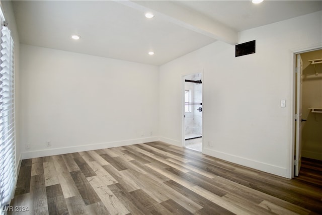 empty room featuring beamed ceiling and hardwood / wood-style flooring