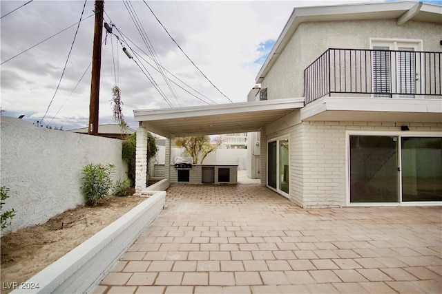 view of patio / terrace featuring a grill, a balcony, and exterior kitchen