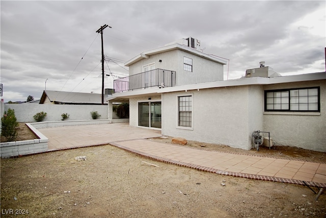 rear view of property featuring a balcony and a patio area