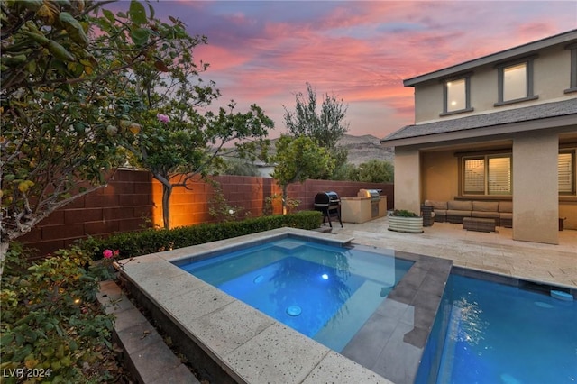 pool at dusk featuring area for grilling and an outdoor living space