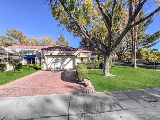 view of front of property with a garage, a tiled roof, concrete driveway, stucco siding, and a front lawn