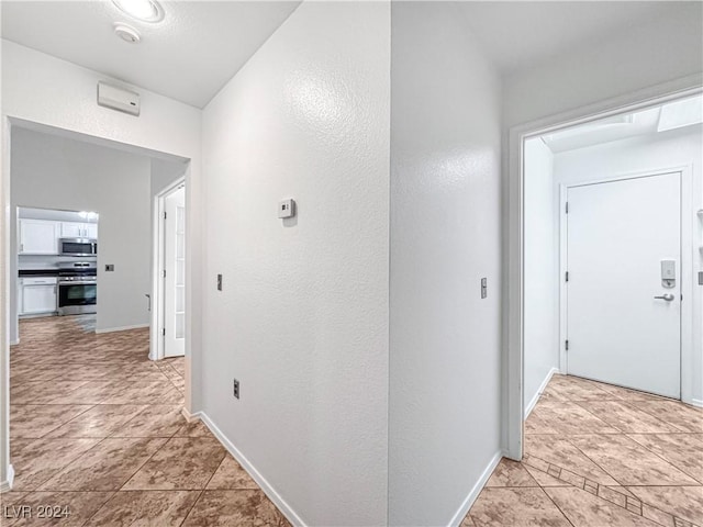 hallway featuring light tile patterned flooring and baseboards