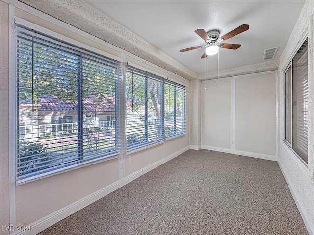 carpeted spare room with baseboards, visible vents, and ceiling fan