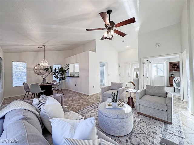 living area with ceiling fan with notable chandelier, high vaulted ceiling, light tile patterned flooring, and baseboards