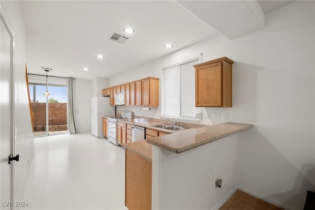 kitchen featuring white appliances, sink, hanging light fixtures, light stone countertops, and kitchen peninsula