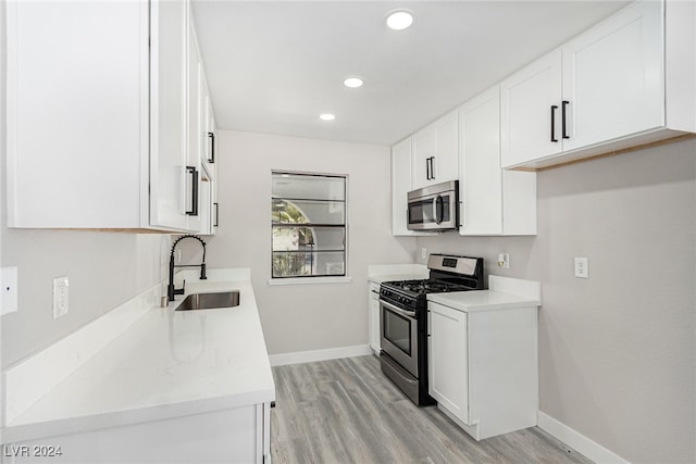 kitchen with white cabinetry, sink, light hardwood / wood-style floors, and appliances with stainless steel finishes