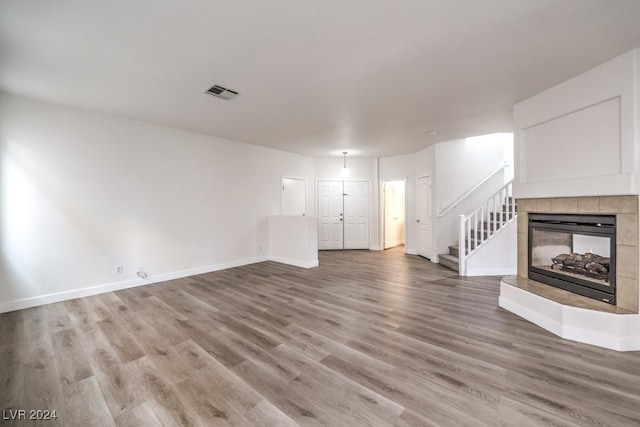 unfurnished living room with a tiled fireplace and hardwood / wood-style flooring