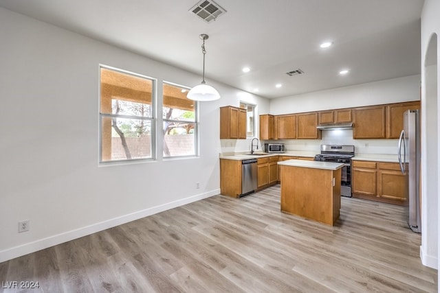 kitchen with light hardwood / wood-style floors, a center island, pendant lighting, and appliances with stainless steel finishes