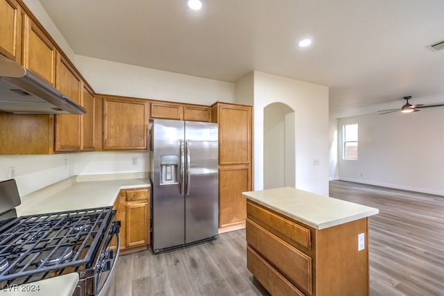 kitchen with a center island, black gas stove, stainless steel fridge, light wood-type flooring, and extractor fan