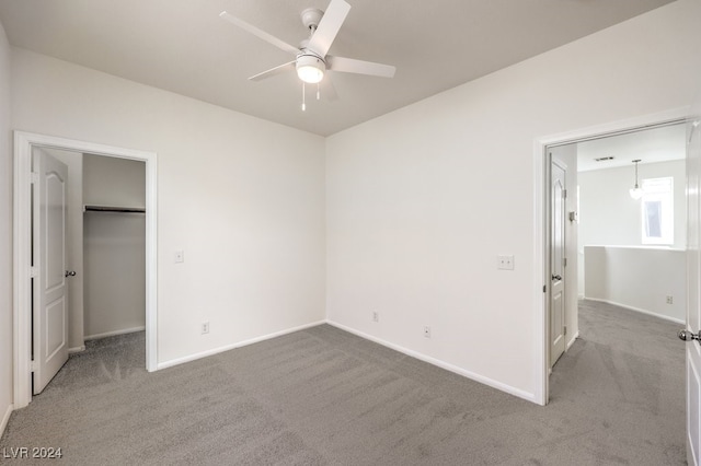 unfurnished bedroom featuring ceiling fan, a closet, carpet, and a spacious closet