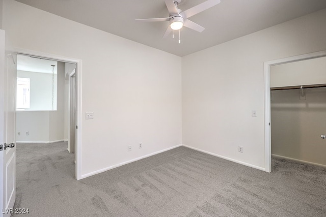 unfurnished bedroom with ceiling fan, light carpet, and a closet