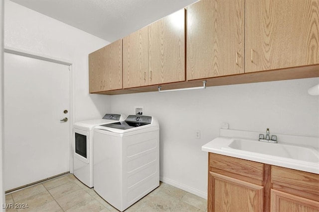 washroom featuring washing machine and dryer, sink, and cabinets