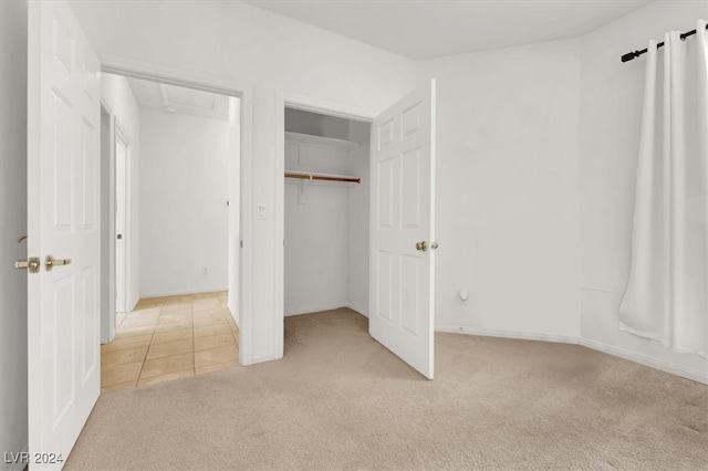 unfurnished bedroom with light colored carpet and a closet