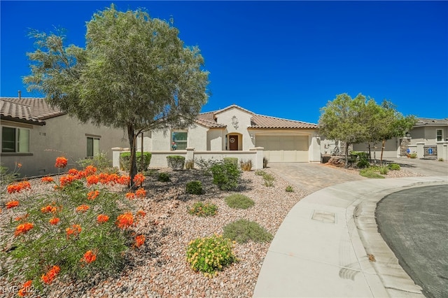 mediterranean / spanish-style home featuring an attached garage, a tile roof, decorative driveway, and stucco siding