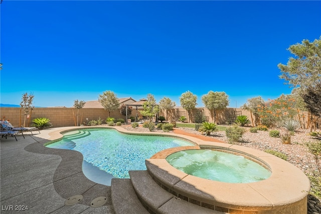 view of swimming pool with a fenced backyard and a pool with connected hot tub