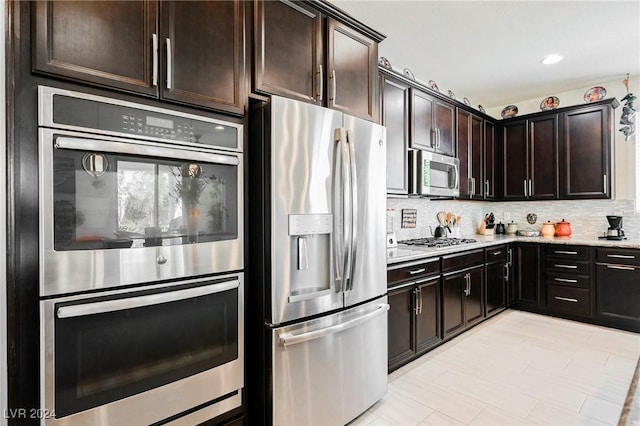 kitchen featuring stainless steel appliances, recessed lighting, tasteful backsplash, dark brown cabinetry, and light stone countertops