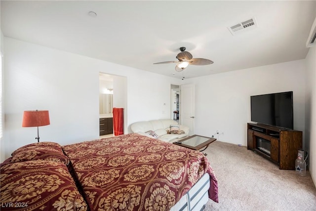 bedroom featuring light carpet, a glass covered fireplace, visible vents, and a ceiling fan