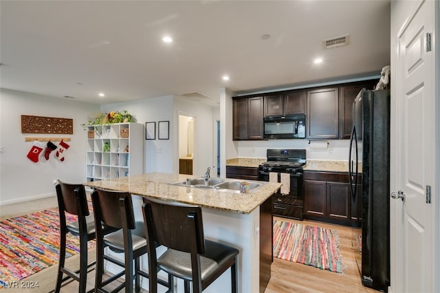 kitchen with sink, a center island with sink, light hardwood / wood-style flooring, and black appliances