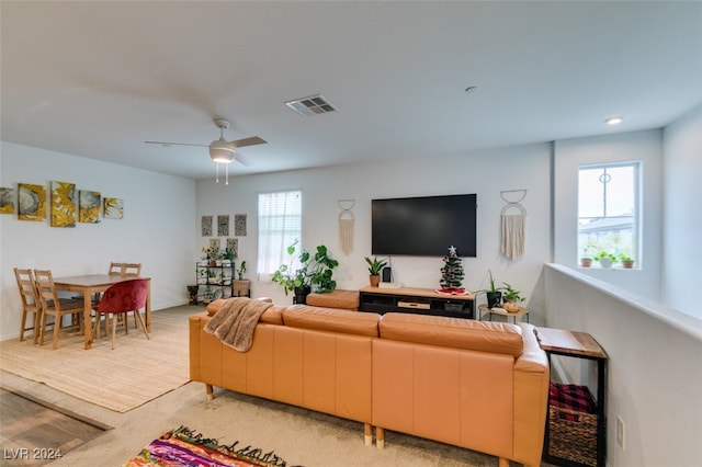 living room with ceiling fan, plenty of natural light, and light colored carpet