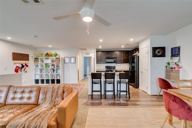 living room with ceiling fan and light hardwood / wood-style flooring