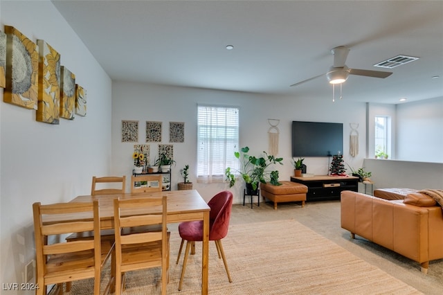 dining space featuring ceiling fan and light carpet