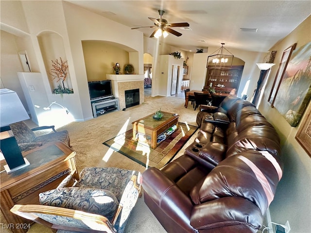 carpeted living room with ceiling fan with notable chandelier and vaulted ceiling