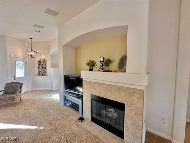 living room with a tile fireplace, carpet floors, and an inviting chandelier