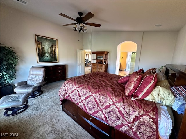 carpeted bedroom with ensuite bath and ceiling fan