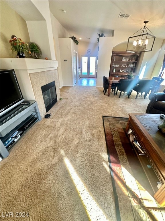 carpeted living room with french doors, a tile fireplace, and a chandelier