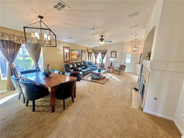 dining space with ceiling fan with notable chandelier, carpet floors, and a wealth of natural light