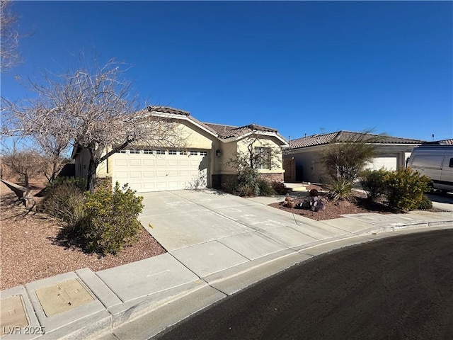 view of front facade with a garage, concrete driveway, a tile roof, and stucco siding