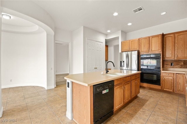 kitchen featuring a kitchen island with sink, sink, light tile patterned floors, and black appliances