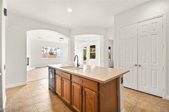 kitchen featuring dishwasher, light tile patterned floors, a kitchen island with sink, and sink