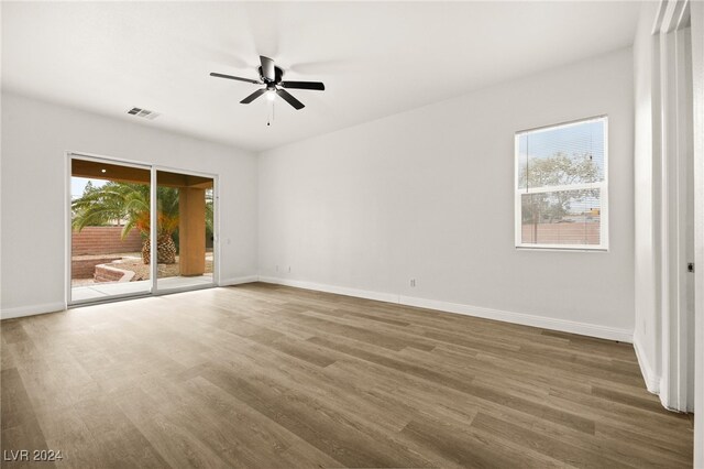 empty room with ceiling fan, plenty of natural light, and dark hardwood / wood-style floors