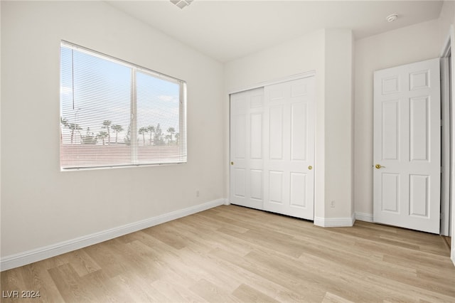 unfurnished bedroom with a closet and light hardwood / wood-style flooring