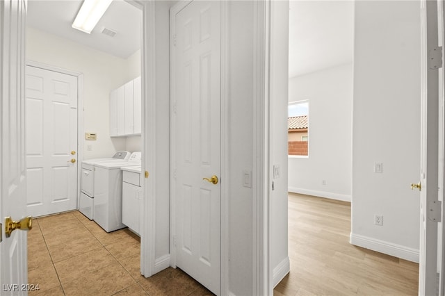 laundry room featuring cabinets, light tile patterned floors, and washing machine and clothes dryer