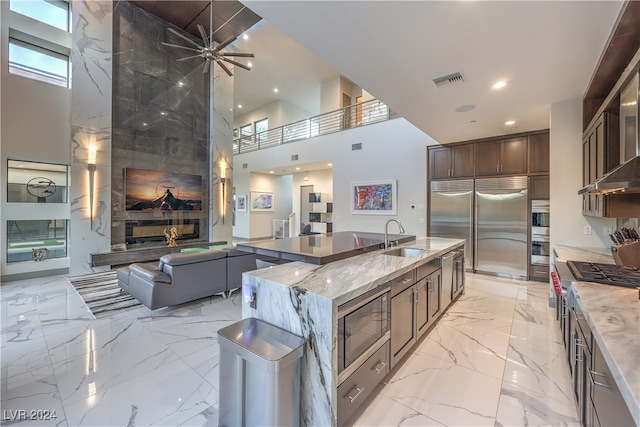 kitchen featuring built in appliances, light stone counters, a spacious island, and a high ceiling