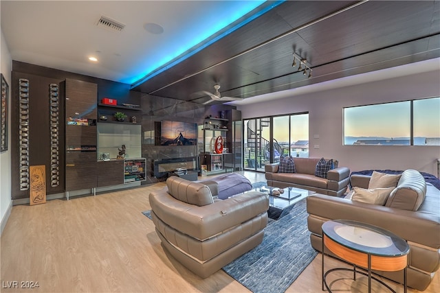 living room featuring a tiled fireplace, ceiling fan, and light hardwood / wood-style flooring