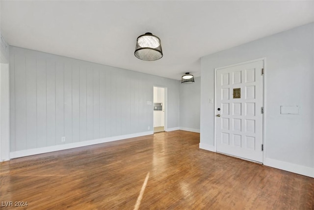 empty room with wood walls and hardwood / wood-style floors