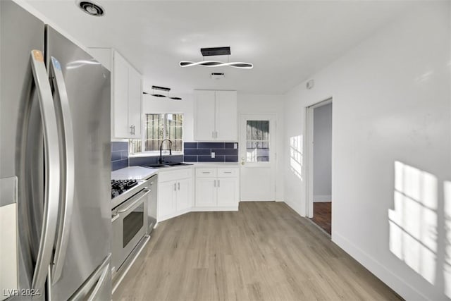 kitchen with sink, white cabinetry, stainless steel appliances, and light hardwood / wood-style flooring