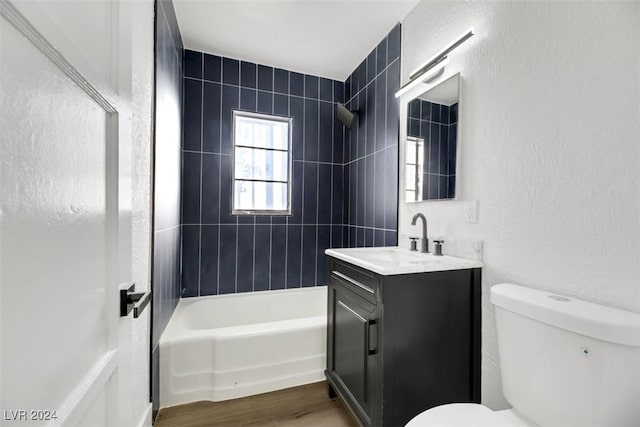 full bathroom featuring hardwood / wood-style flooring, tiled shower / bath combo, toilet, and vanity