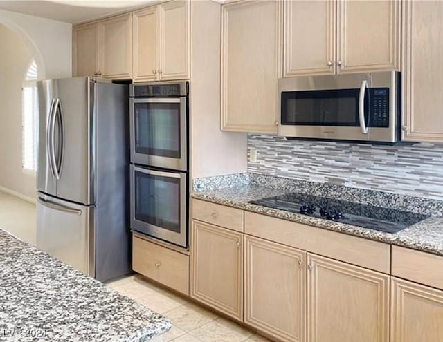 kitchen with tasteful backsplash, light tile patterned floors, light brown cabinetry, appliances with stainless steel finishes, and light stone counters