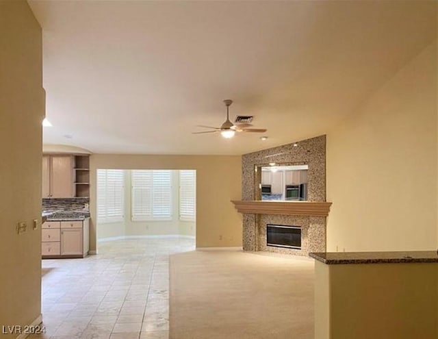 unfurnished living room with ceiling fan, a high end fireplace, and light tile patterned floors