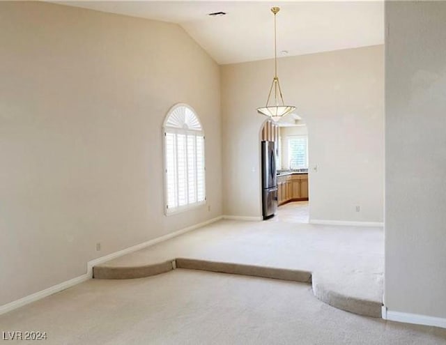 spare room featuring carpet flooring and vaulted ceiling