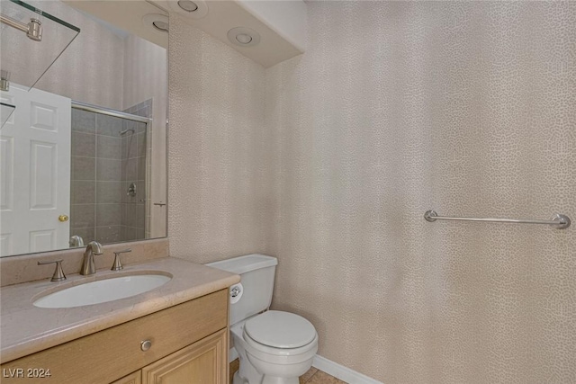 bathroom featuring a shower with door, vanity, and toilet